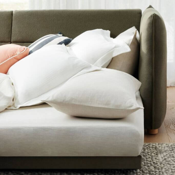 Closeup of a dark green sleeper sofa puled out in a brightly lit living space.