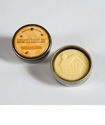 Yellow beeswax lotion in a silver tin on a grey background. Click to visit Bluecorn Beeswax website.