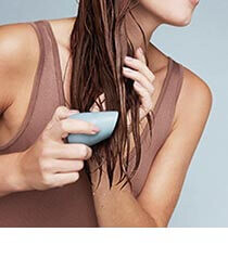 A woman washing her hair with a blue shampoo bar. Click to visit the EcoFreax website.