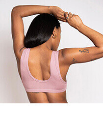 A woman wearing a pink sports bra with tattoos on her arm. Click to visit the Mary Young website.