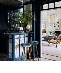 A dark blue home bar with a bright living room in the background.