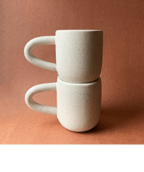 Two white mugs on a pink-brown background.