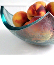 Closeup of a glass bowl filled with peaches. Click to visit the Hanscomb Glass Studio website.