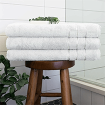 Three folded white towels sitting on a wooden bench. Click to visit the Cariloha website.