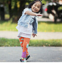 A little girl playing outside wearing colourful pants and a denim vest. Click to visit Q for Quinn website.