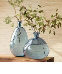 VIVATERRA<br />
Furniture + Decor Two blue glass vases with greenery inside.