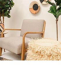 A modern wood-framed chair sitting next to plants and a side table.