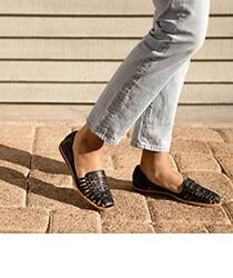 Closeup of a pair of feet wearing black closed toe sandals.
