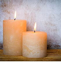 Two off-white candles on a wooden ledge.
