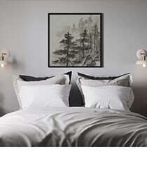 A framed drawing of a forest hanging over a bed.