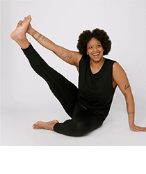 A smiling woman stretching her leg in black activewear.