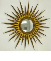 A gold sunburst mirror hanging on a wall.