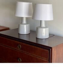 Two wide vintage lamps on a wooden dresser.