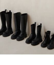 Black boots lined up against a white wall.
