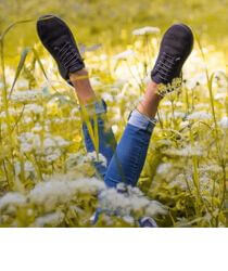 A pair of legs in sneakers sticking up out of a field of flowers.