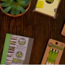 Various school supplies sitting on a wooden table next to a plant.