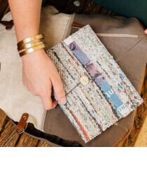 A hand holding a journal made of reclaimed newspaper.