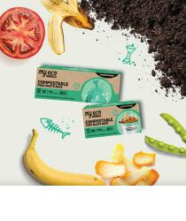 Two boxes of compostable food waste bags next to food scraps on a white background.