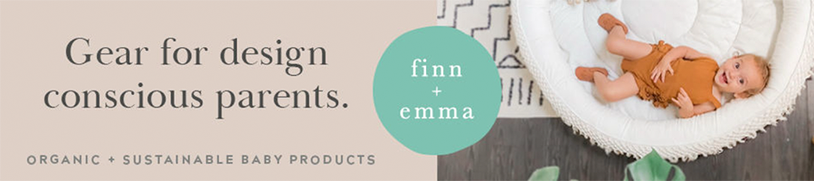 A baby smiling and laying on a white play mat with the words "Finn + Emma. Gear for design conscious parents. Organic + sustainable baby products.